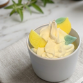 Produktfoto der Zitronentraum Kerze in einer hellen Dose mit Zitronensorbet-Duft, präsentiert in einer gemütlichen Frühlings-Dekoration mit weiteren Lichtlein-Glaskerzen im Hintergrund.