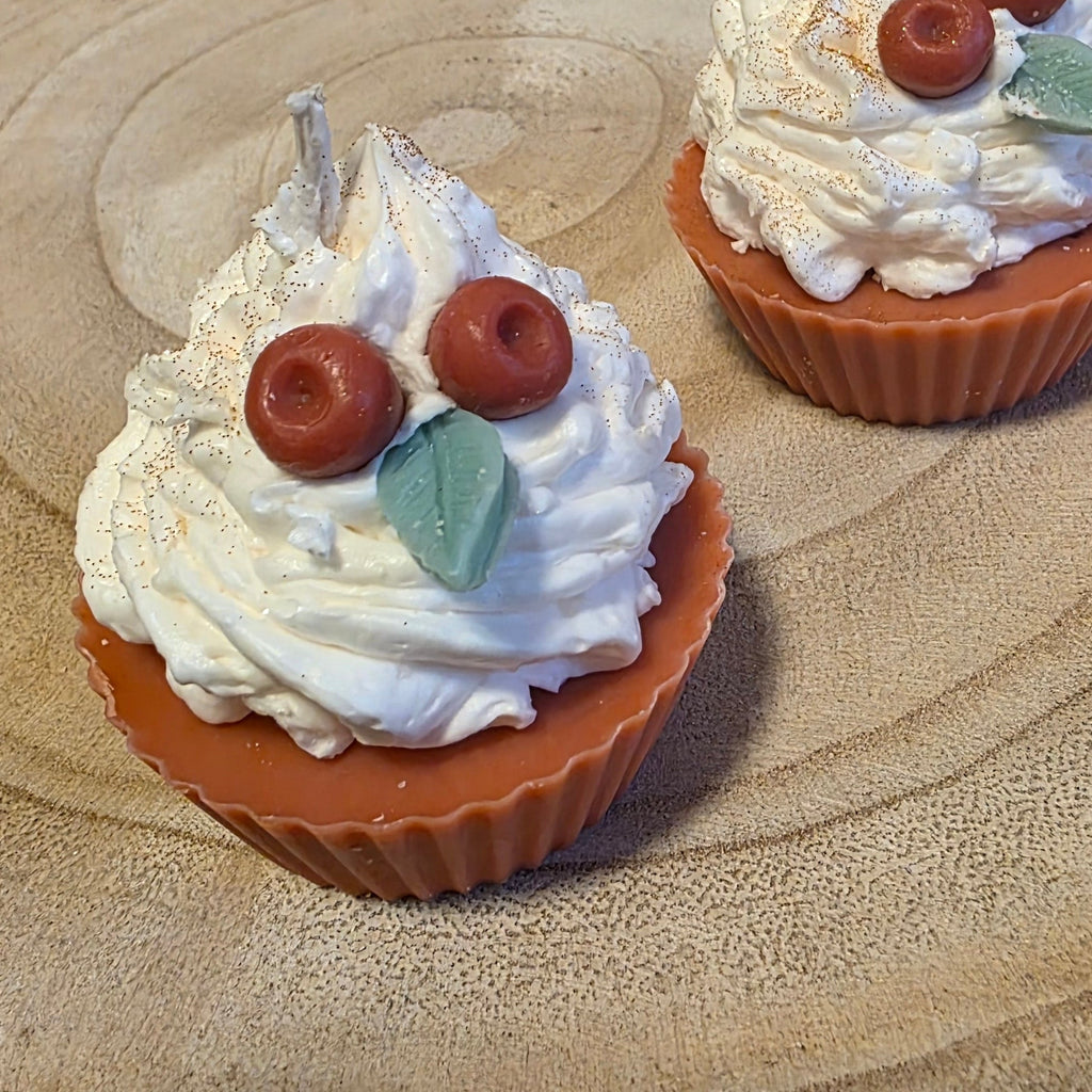 Cupcake Kerze mit Goldpuder. Täuschend echt mit Rotem Boden und Sahnehaube aus Wachs. Echt aussehende Kirschen und Blätter in der Sahnehaube. Steht auf einem Holztablett
